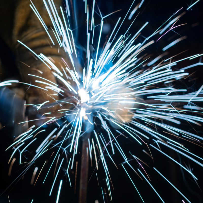 Young man with protective mask welding in a factory